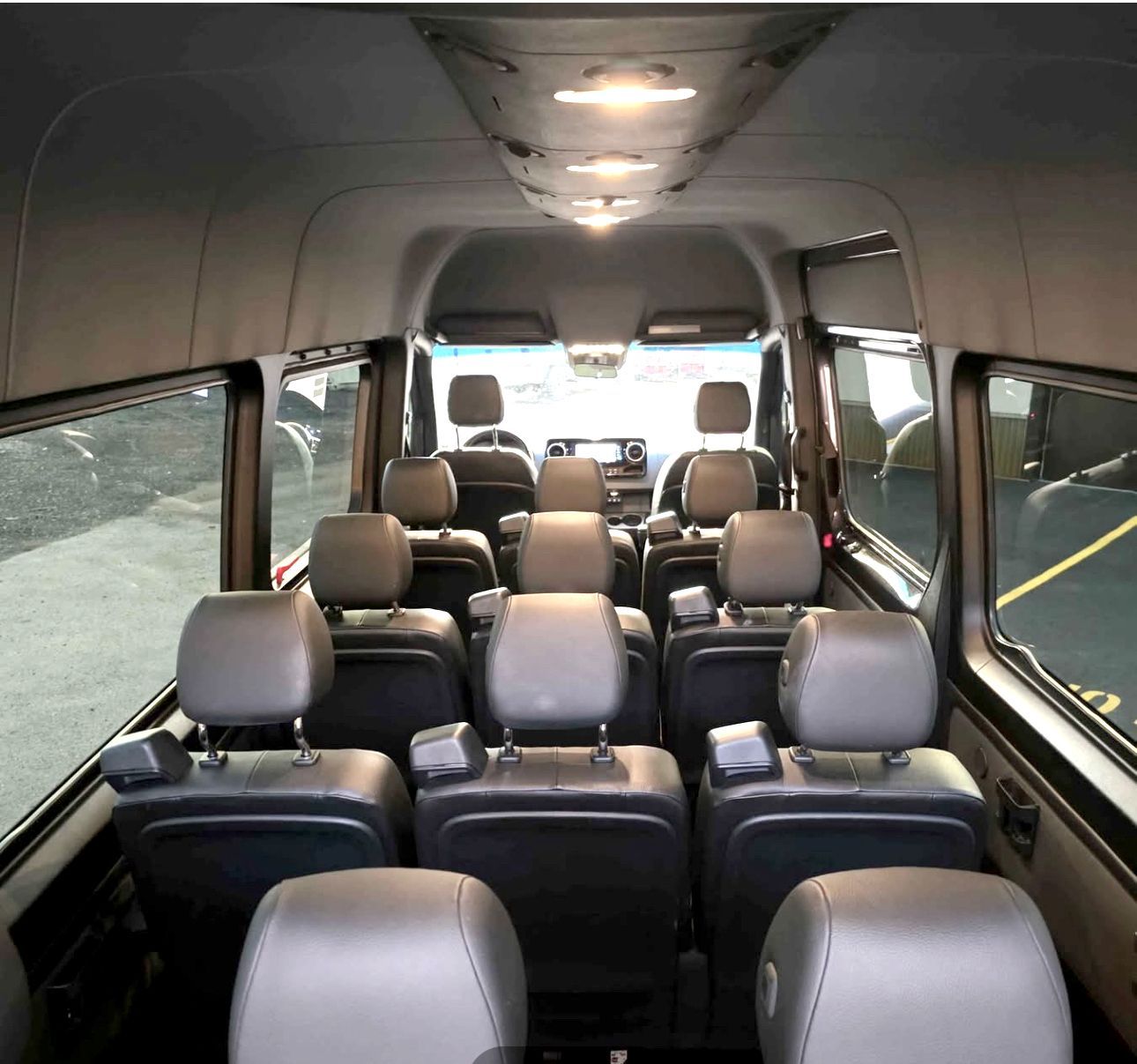 A 15 passenger van inside view from the back with leather seats.