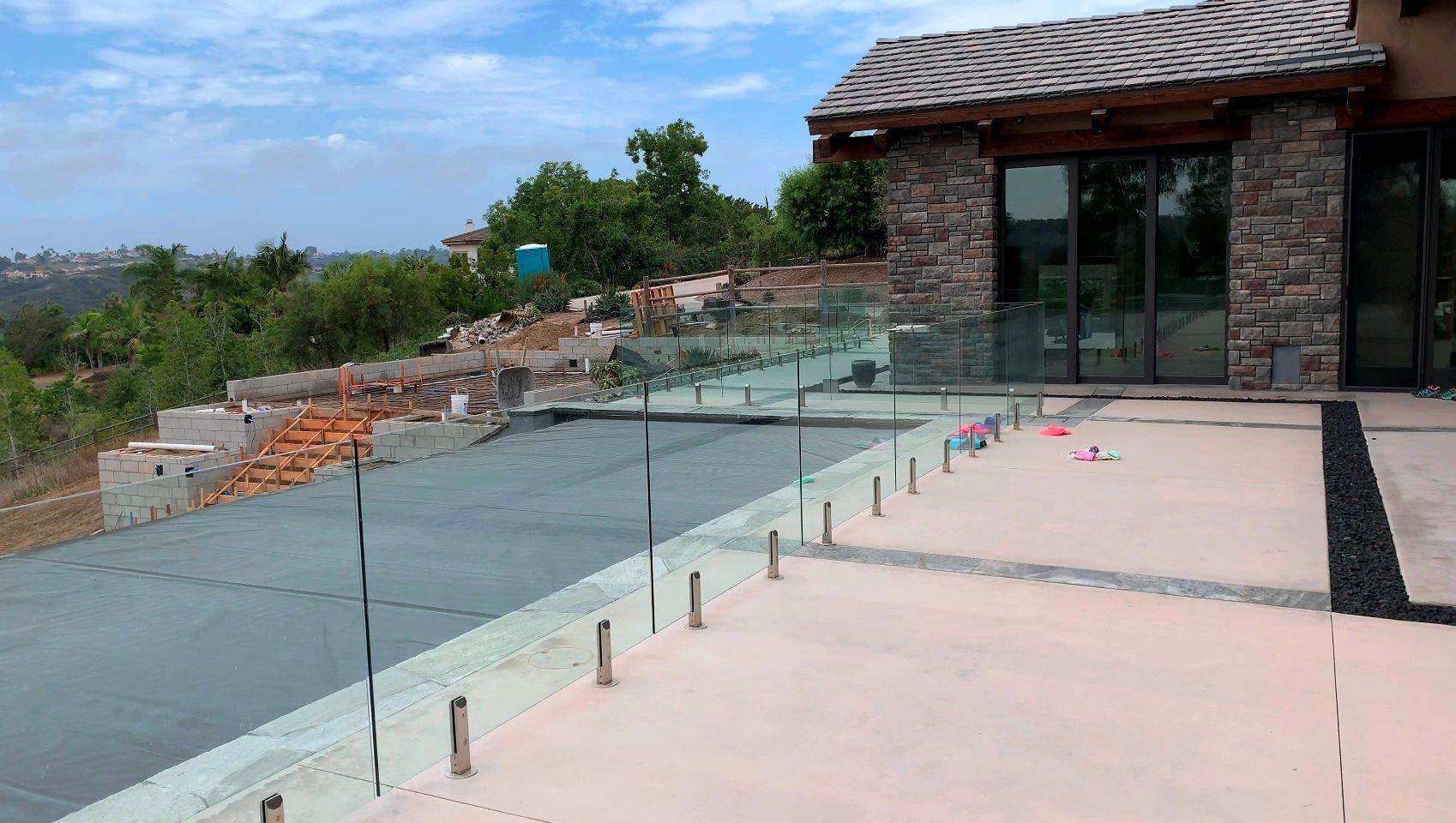 Glass railing on patio with view of landscape and building.