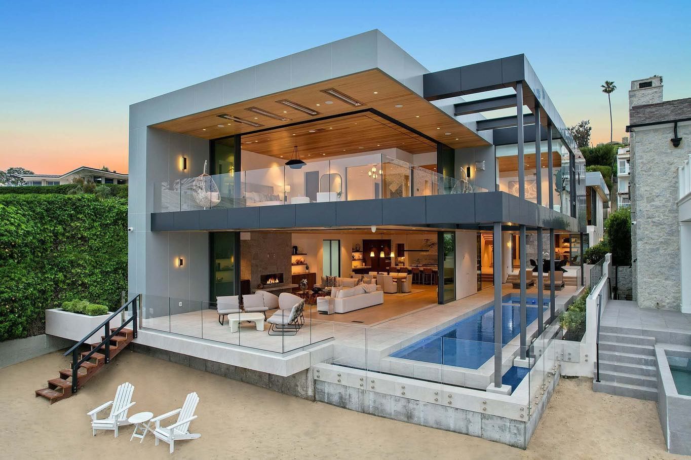 Modern house with pool and outdoor seating. Blue sky.