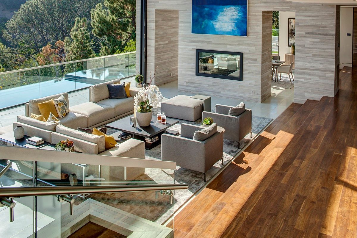 Modern living room with fireplace, pool view, and wooden floors.
