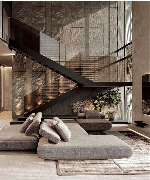 Modern living room with stone wall, black staircase, and gray sectional sofa.