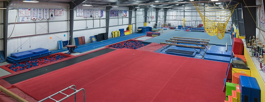 Gym interior with red and blue mats, equipment, and colorful blocks.