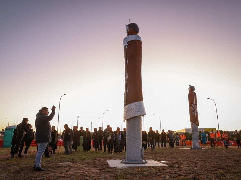 A group of people are standing around a statue in a field.