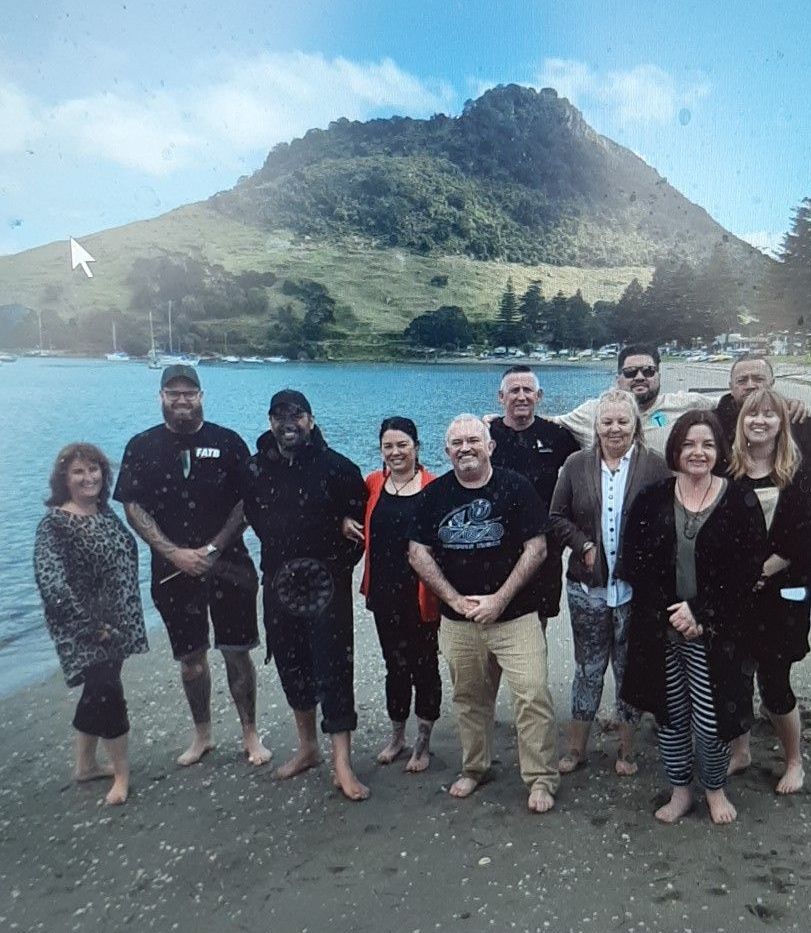 A group of people standing on a beach with a mountain in the background