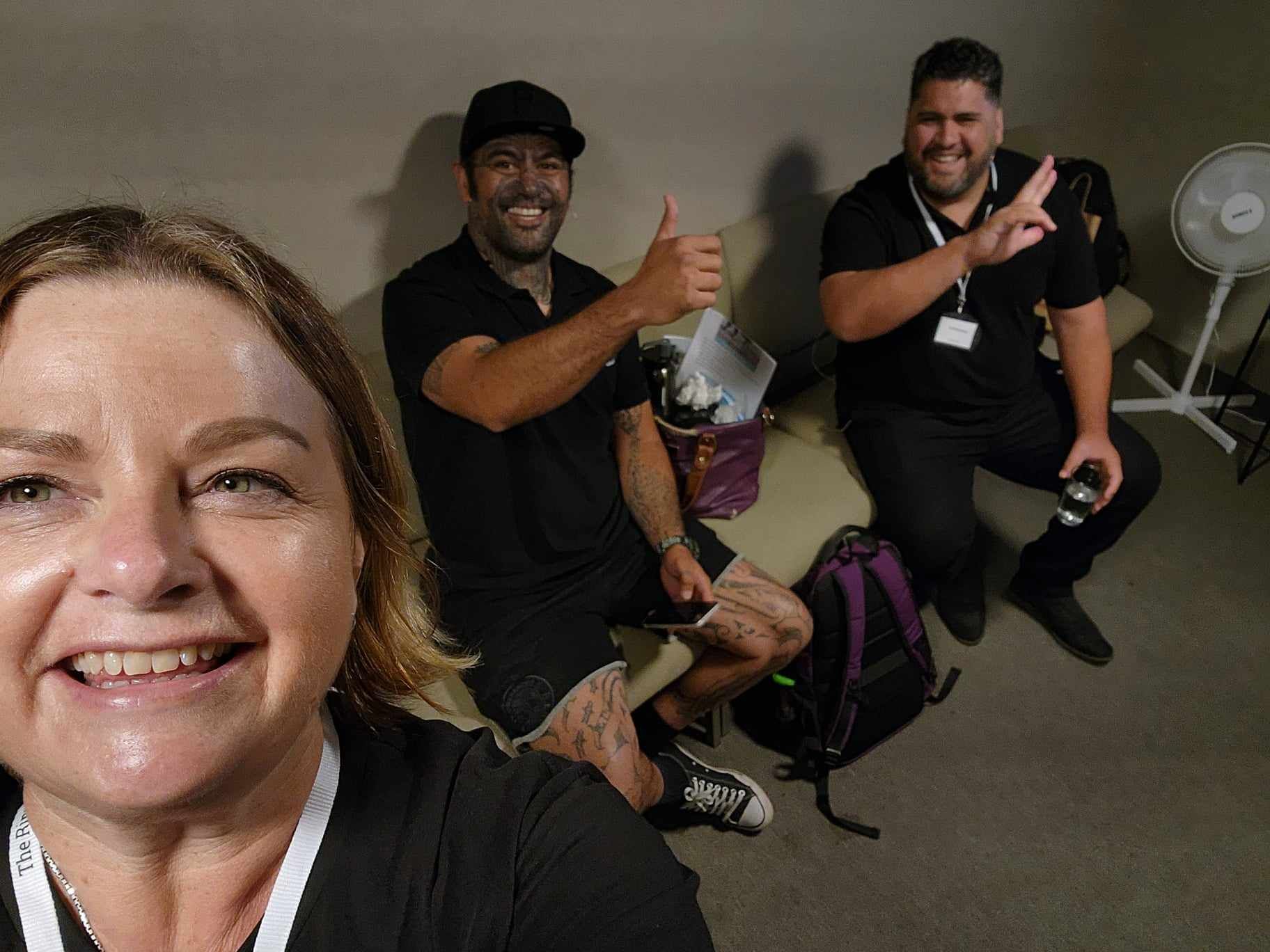 A woman is taking a selfie with two men in a room.