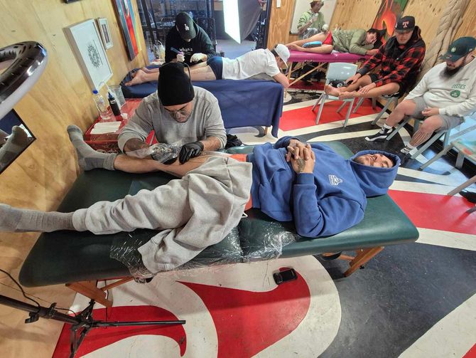A group of people are getting tattoos in a room.