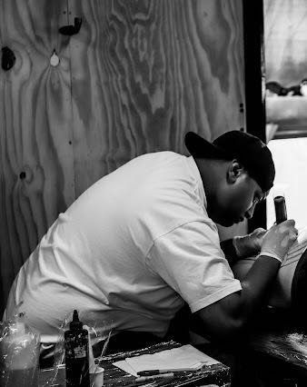 A man is getting a tattoo on another man 's arm.