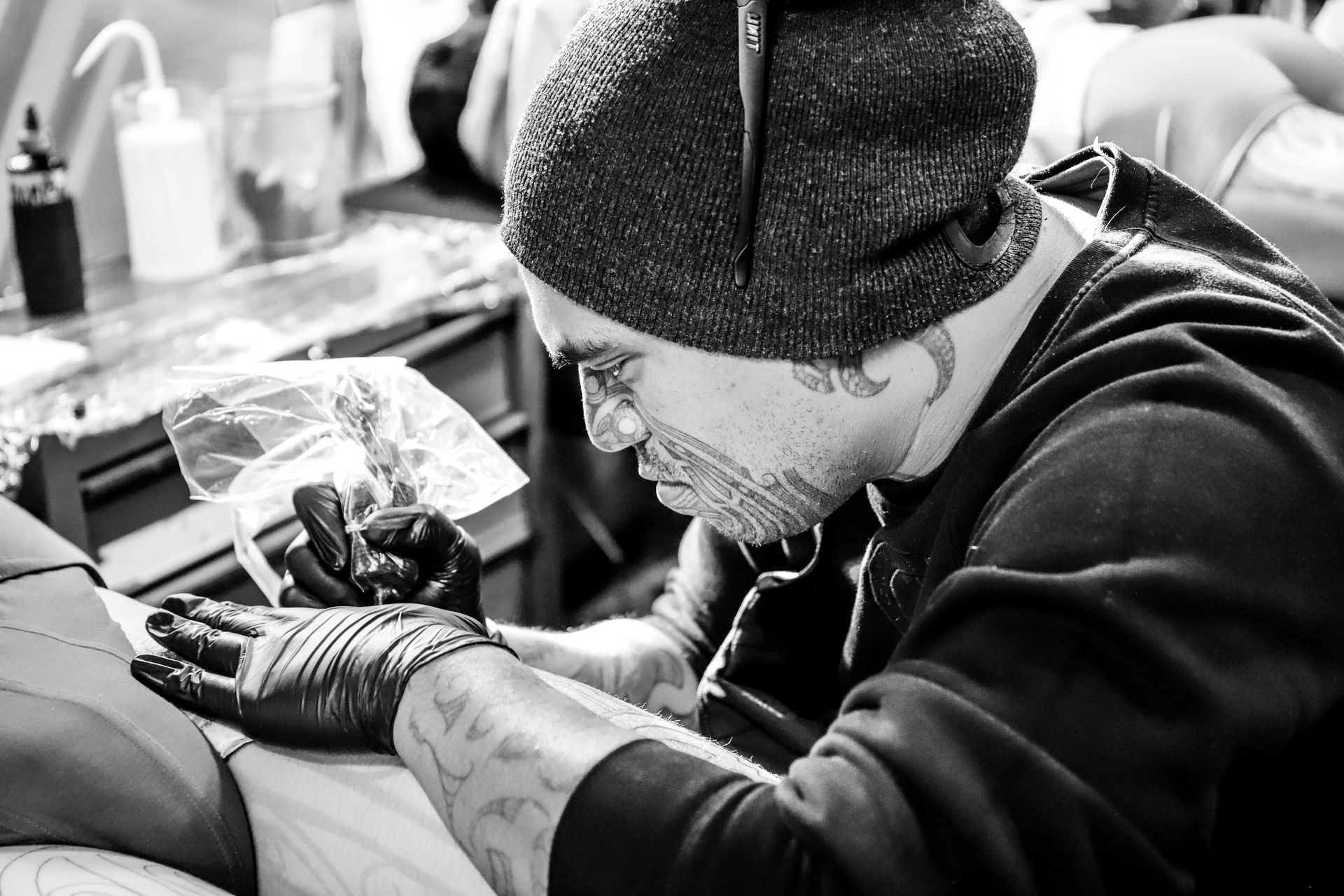 A man is getting a tattoo on another man 's arm.