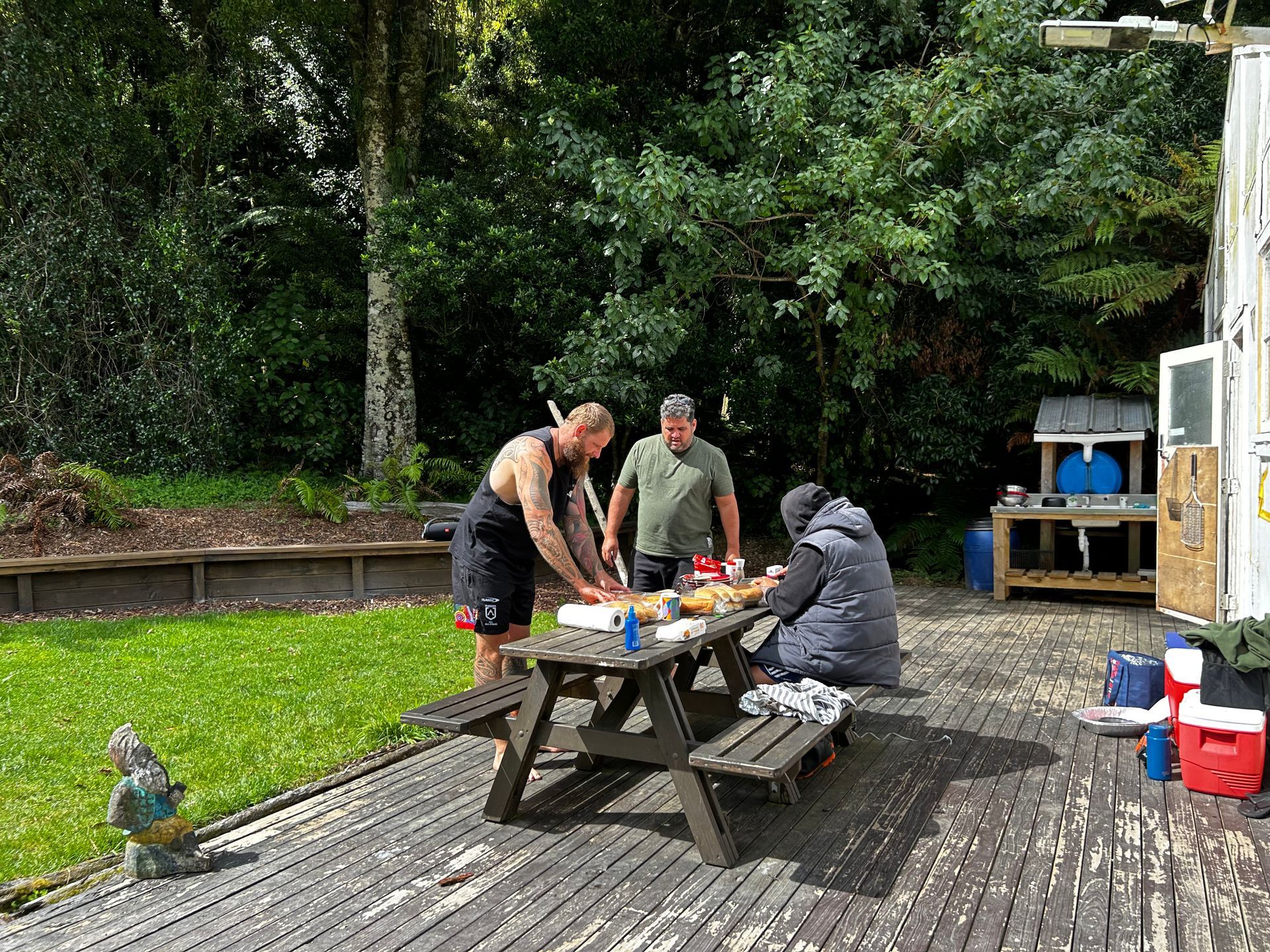A group of people are sitting at a picnic table on a deck.