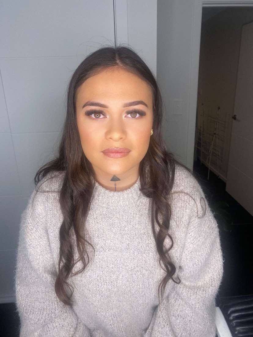 A woman in a sweater is sitting in a chair and looking at the camera.