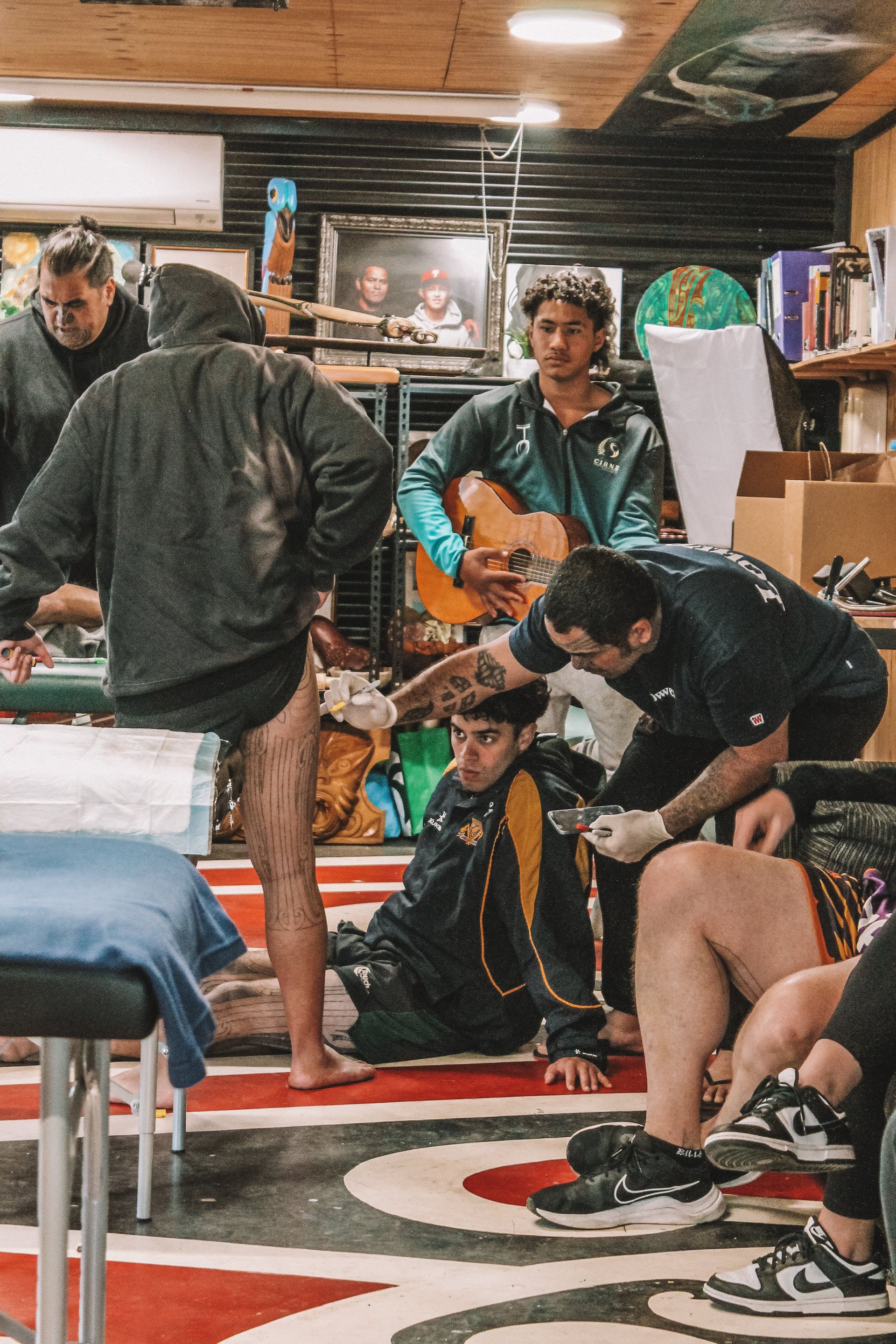 A group of people are getting a tattoo in a room.