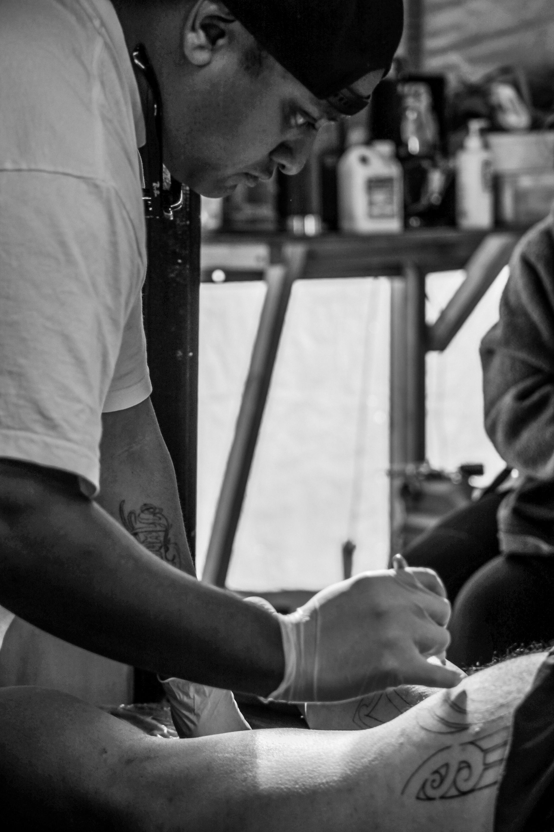 A man is getting a tattoo on another man 's arm.