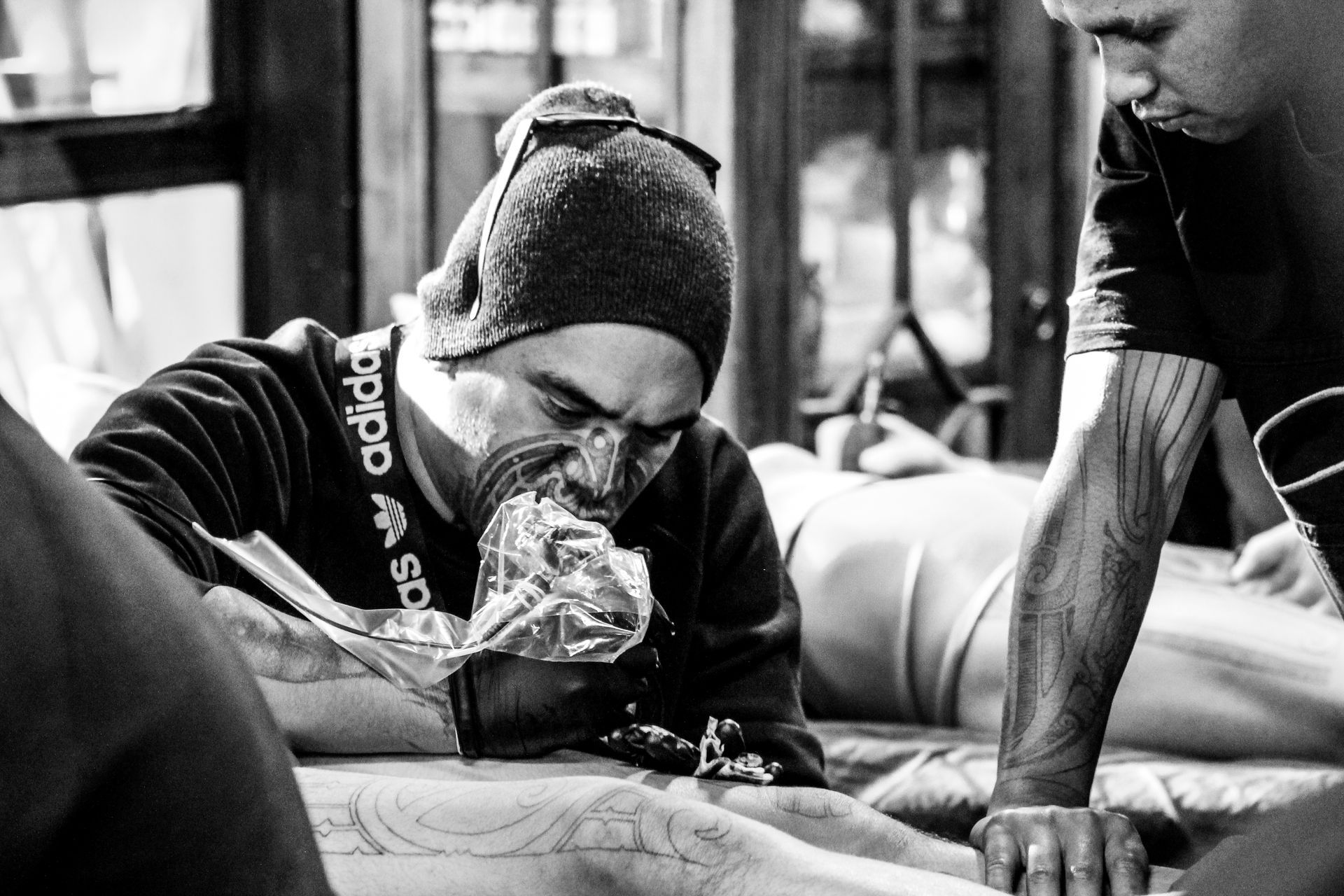 A man is getting a tattoo on another man 's leg.