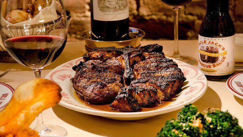 A bottle of wine is sitting on a table next to a plate of food.