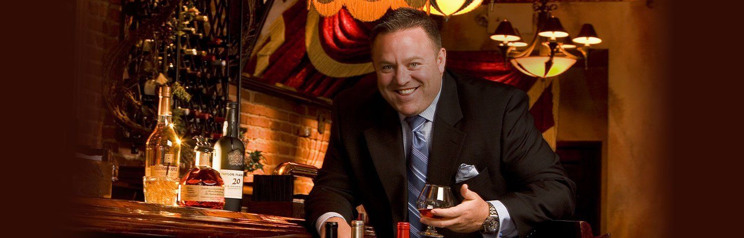 A man in a suit and tie is holding a glass of wine.
