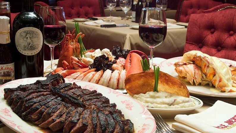 a bottle of black jack wine sits next to a plate of steak, lobster and shrimp at uncle jacks steakhouse