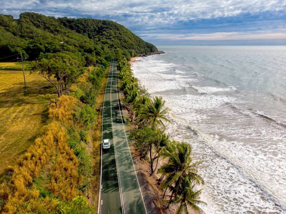 An Aerial View of a Car Driving Down a Road Next to the Ocean — Express City Couriers in Palm Cove, QLD