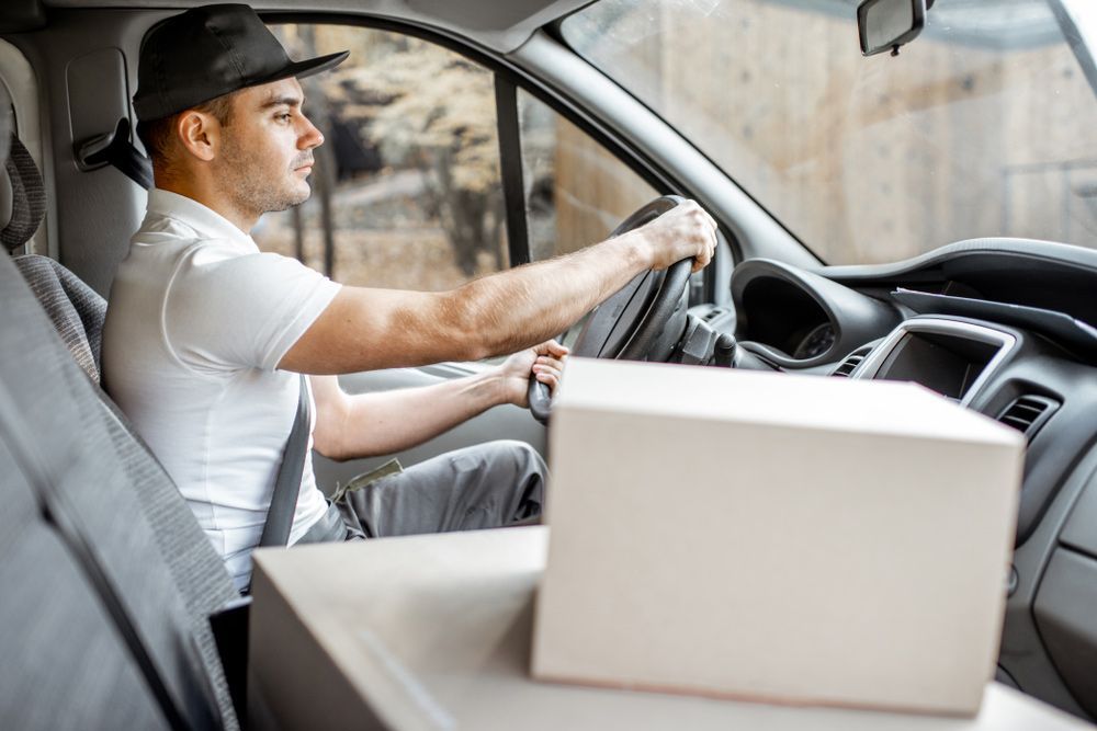 A Delivery Man Is Driving A Van With A Box In The Back Seat — Express City Couriers in Bungalow, QLD