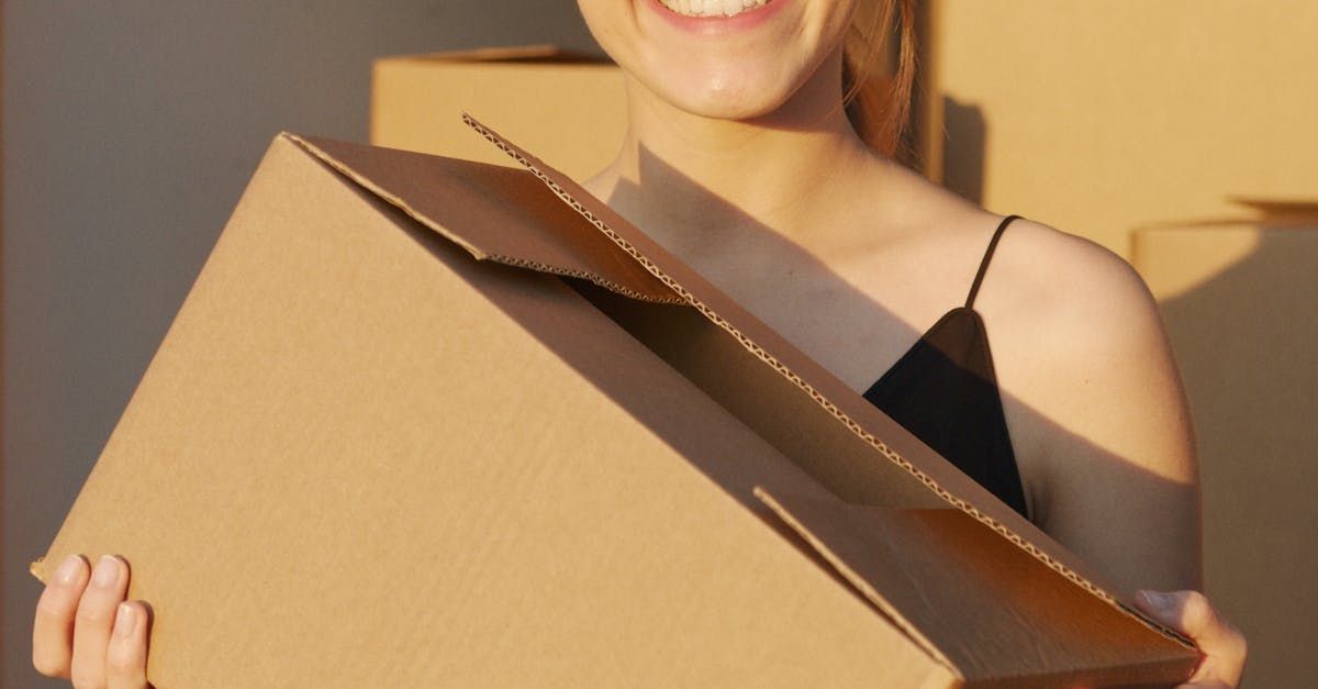 A Woman is Holding a Cardboard Box in Her Hands and Smiling — Express City Couriers in Bungalow, QLD