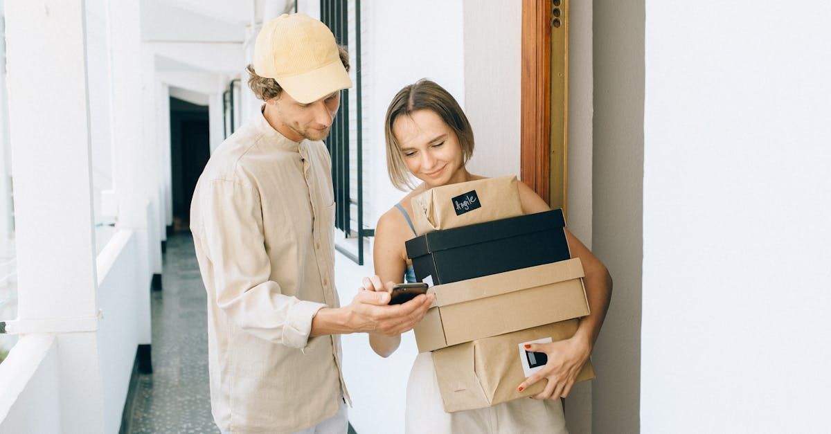A Delivery Man Is Talking On A Cell Phone While Holding A Cardboard Box — Express City Couriers in Bungalow, QLD