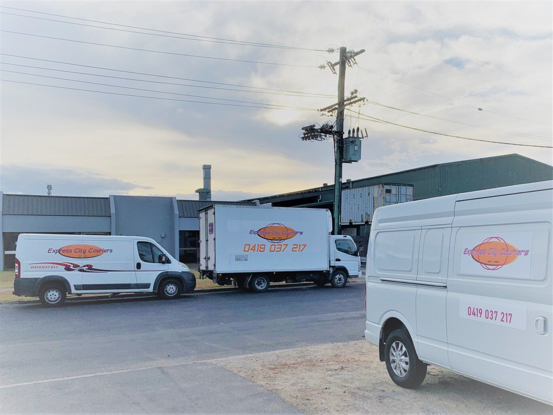 Two White Vans Are Parked In Front Of A Building — Express City Couriers in Bungalow, QLD