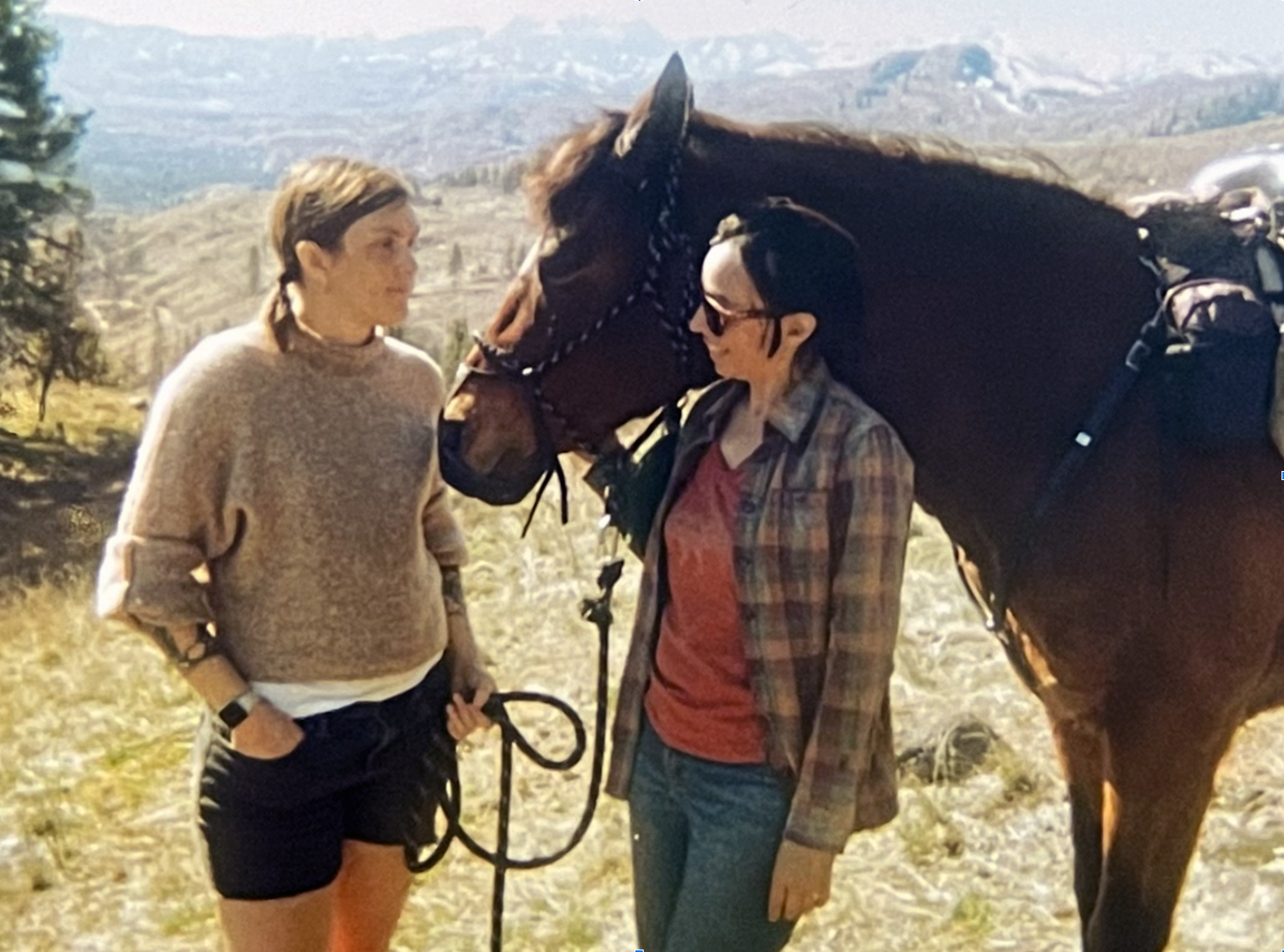 Two women and a horse with mountains in the background