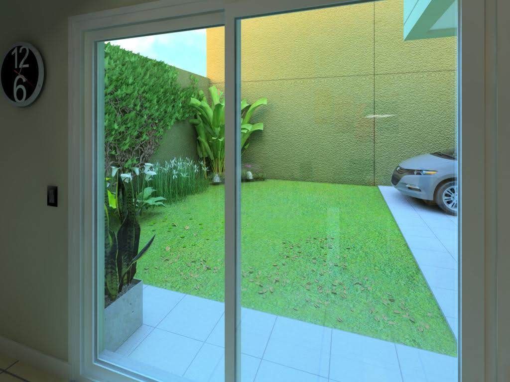 Las puertas corredizas de vidrio se abren a un patio trasero con césped verde, una pared verde densa