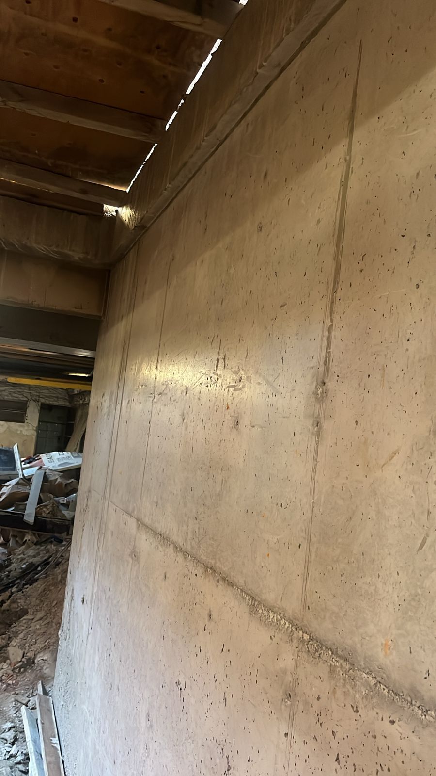 Muro de hormigón bajo vigas de madera, probablemente una obra sin terminar.