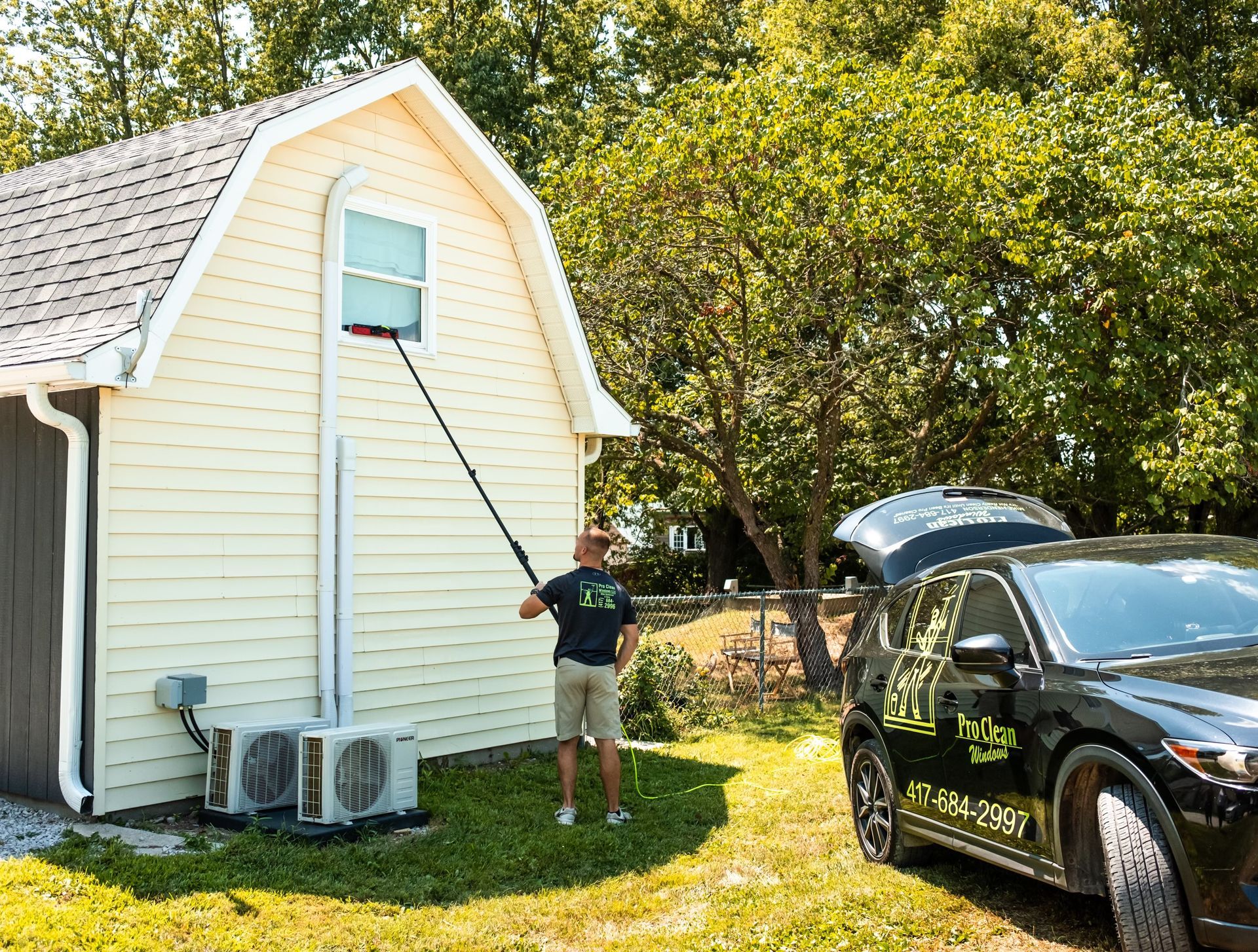 A man is cleaning a window of a garage next to a car.