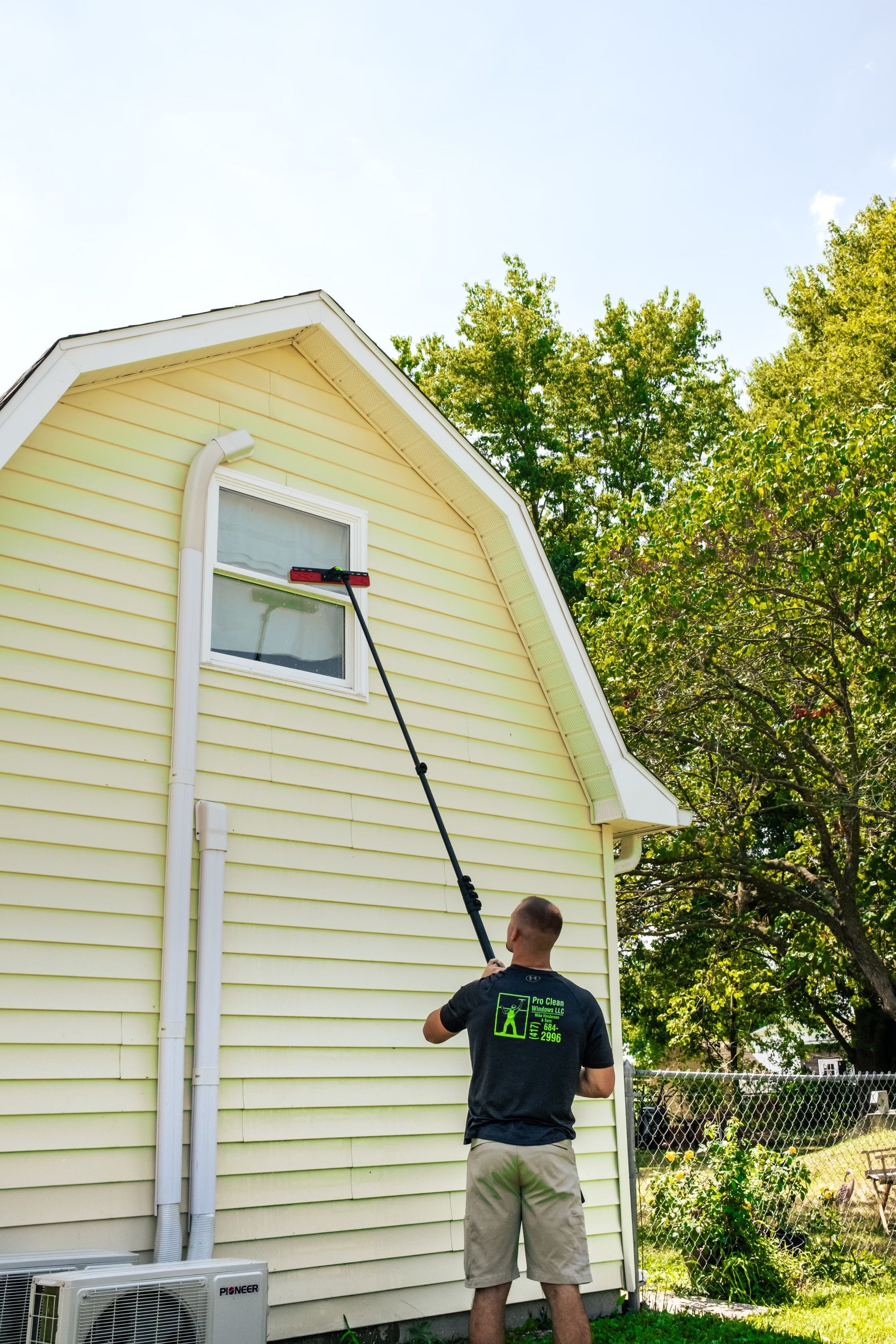 A man is cleaning a window on the side of a house.