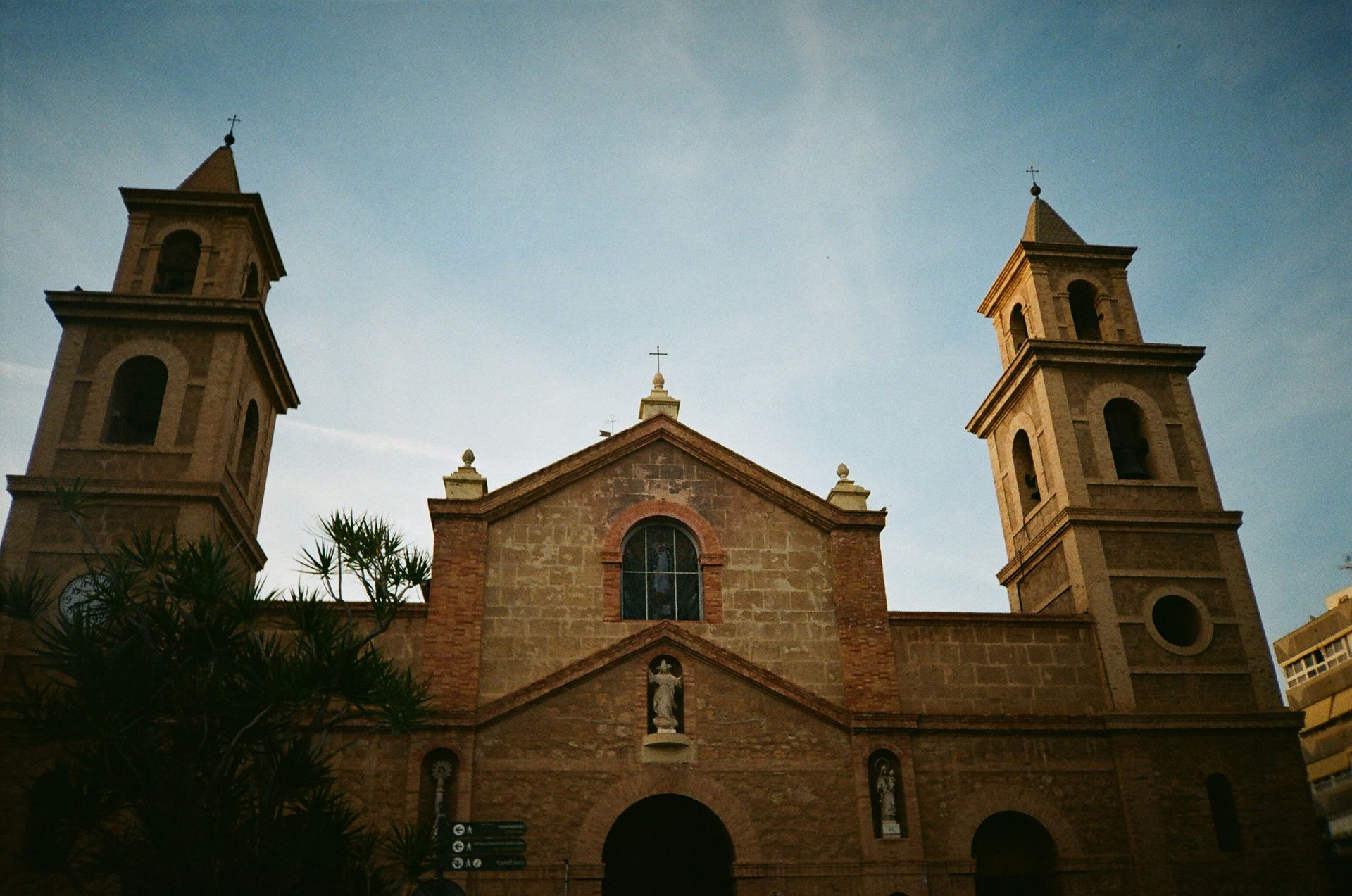 Brick church with two towers under a blue sky.