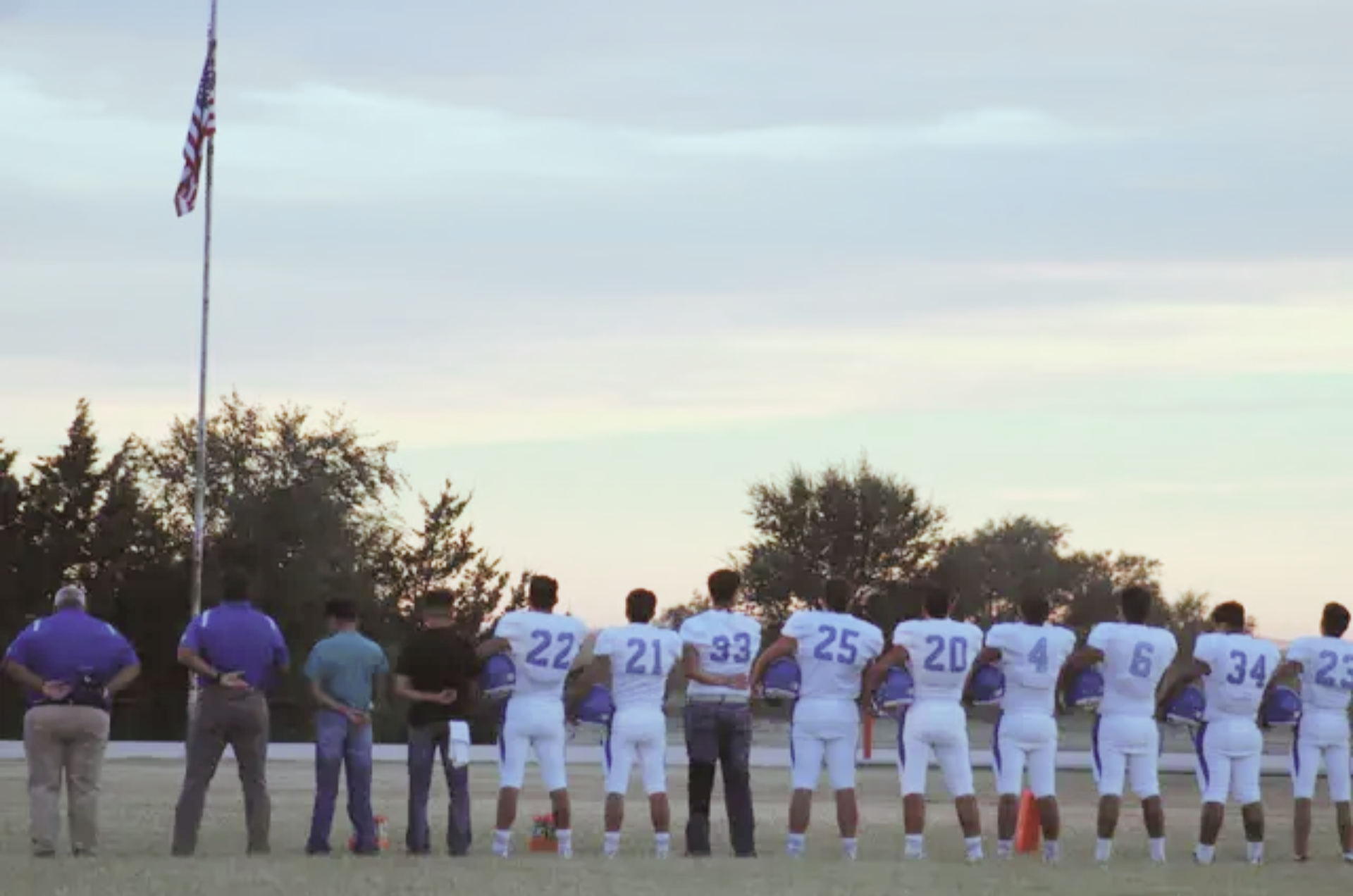 a group of football players stand in front of a flag
