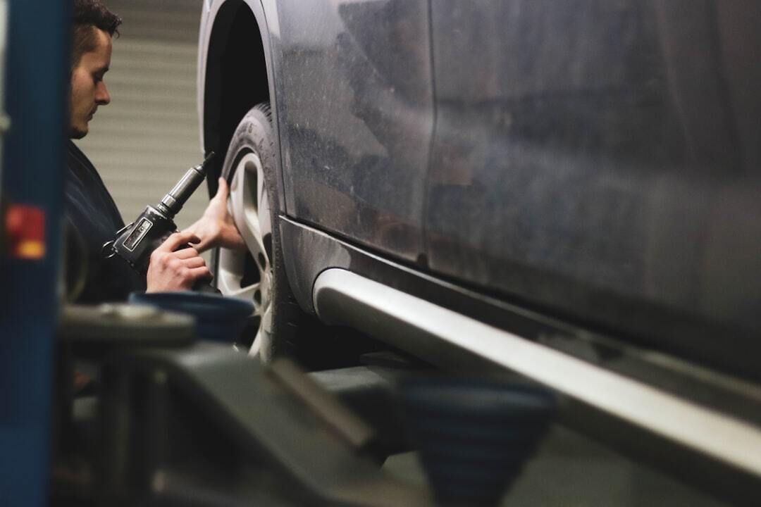 A man is changing a tire on a car in a garage.