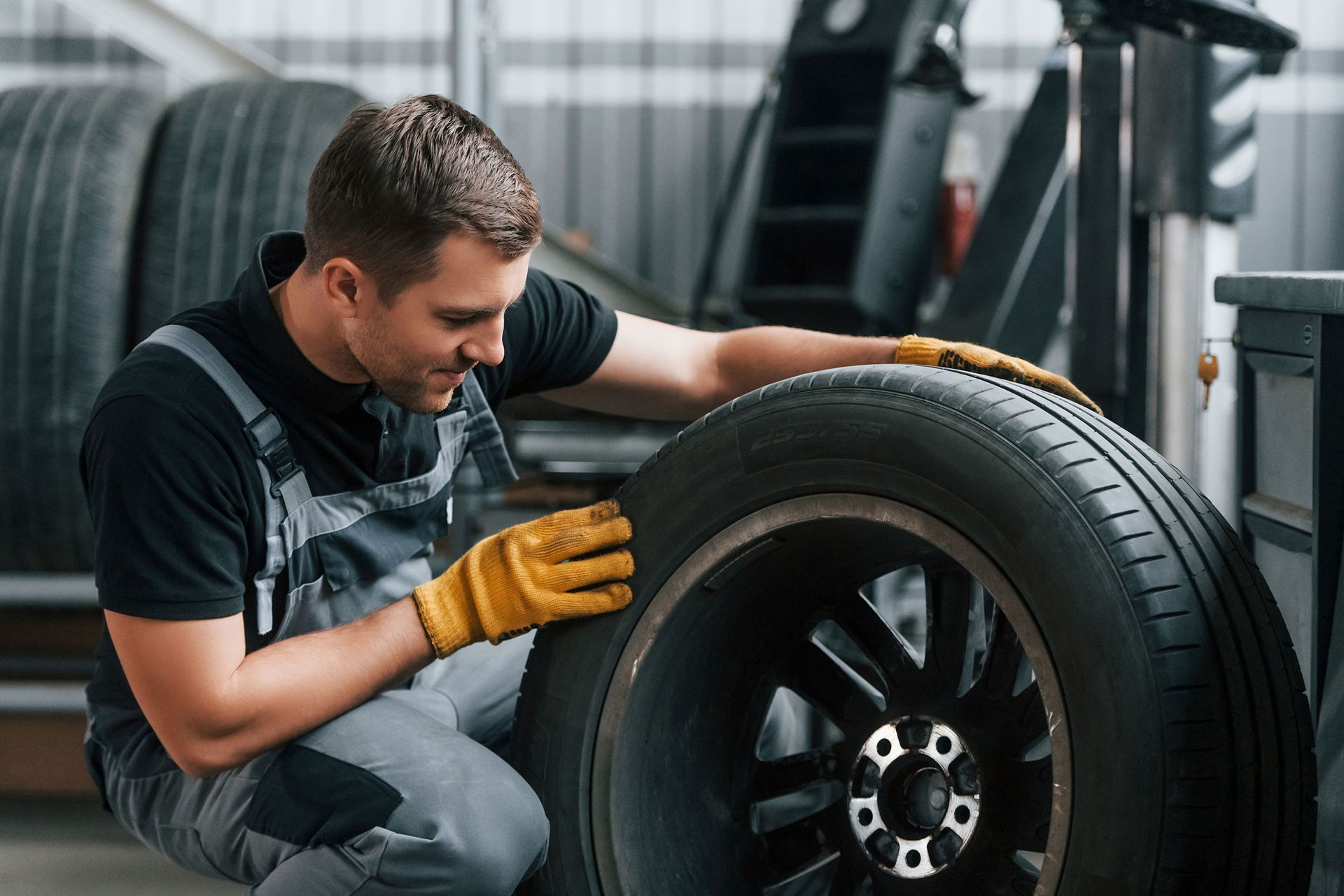 a man is kneeling down next to a tire in a garage .