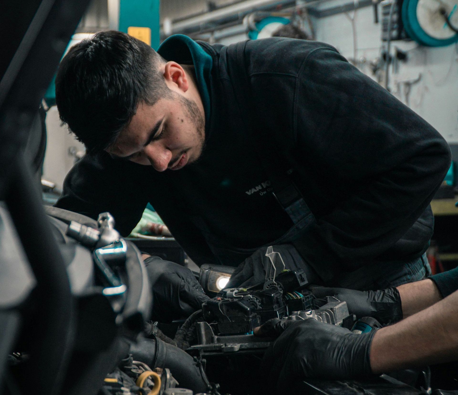 A man is working on the engine of a car in a garage.