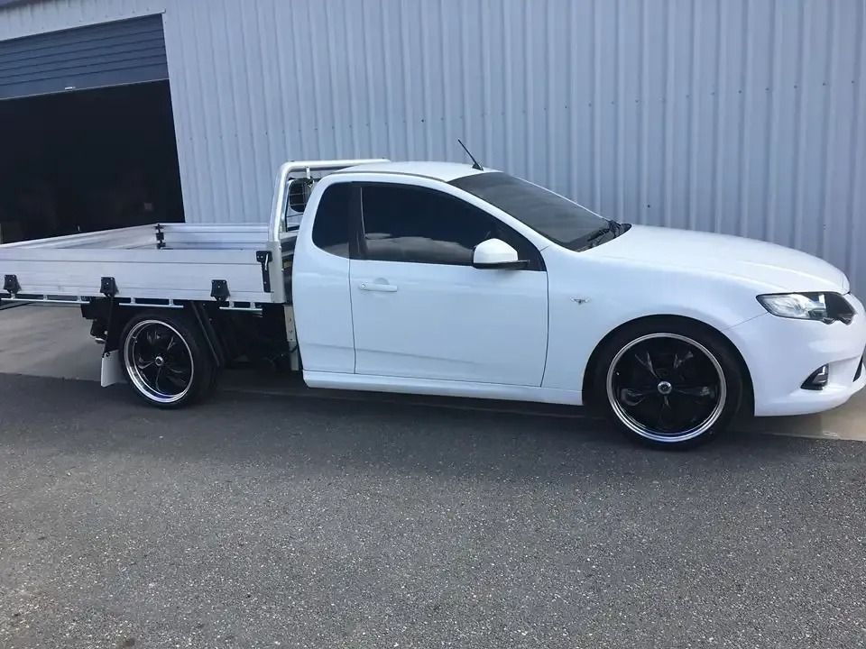 A White Truck With A Flat Bed Is Parked In Front Of A Building — CQ Auto Tint In Kawana, QLD