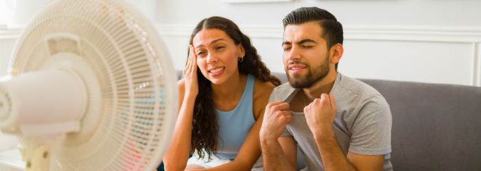 Two Florida tenants sitting in front of a fan, looking hot and distressed due to a broken air conditioner in their rental home