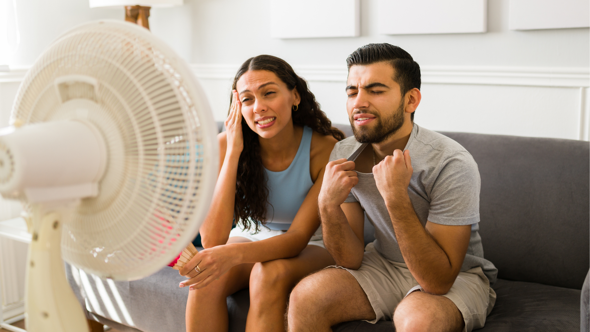 Two tenants sitting in front of a fan in their hot Florida apartment due to broken air conditioning