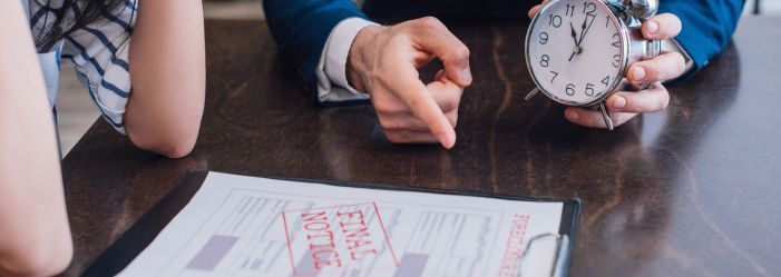 Person pointing to a clipboard with a final notice while holding a clock, symbolizing urgent evictio