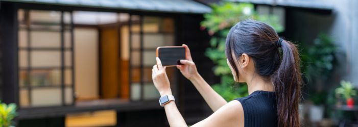 women taking a photo with her phone of her home prior to moving out