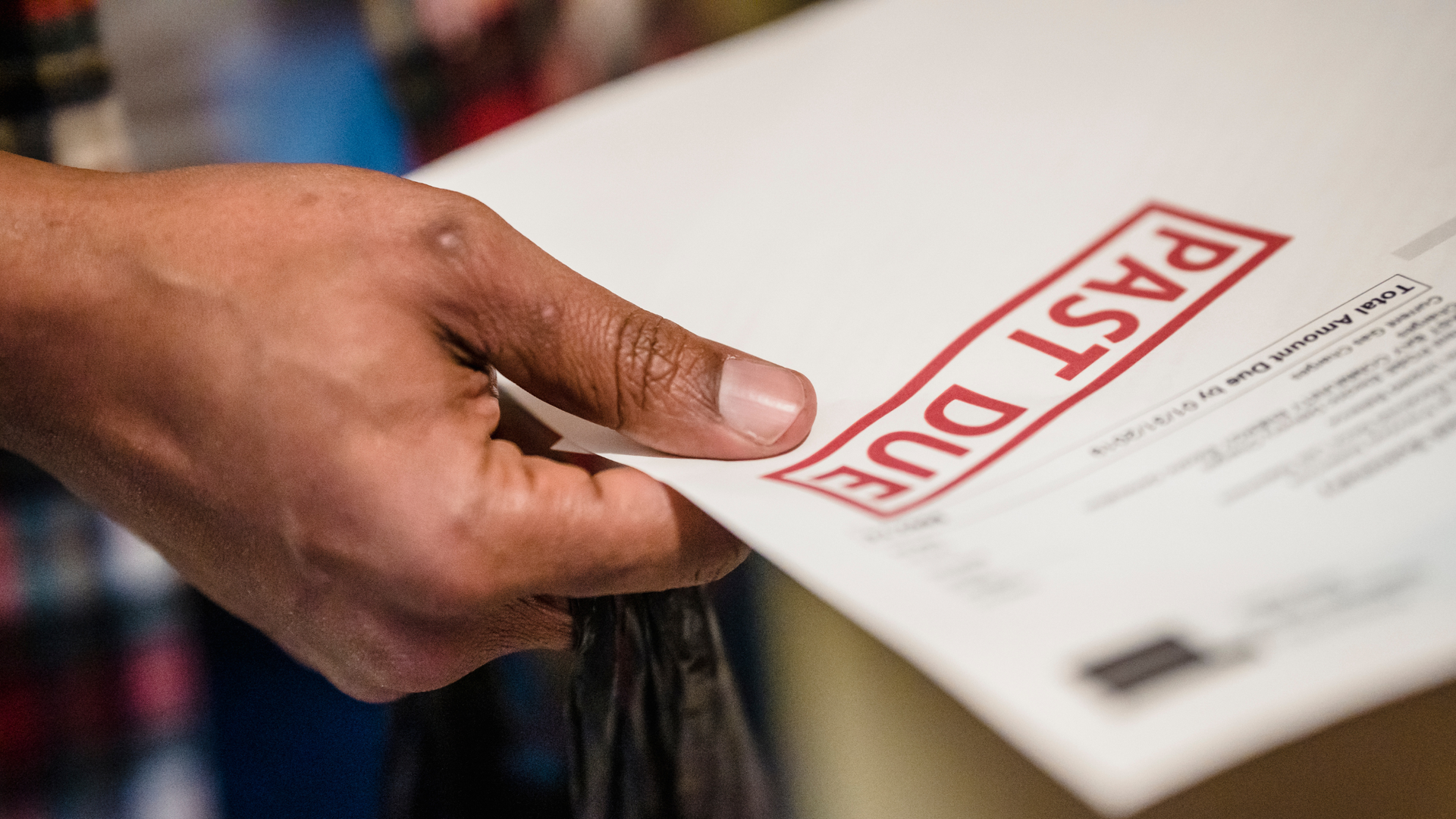 hand holding a paper that has a 'past due' stamp on it representing the collections agencies.