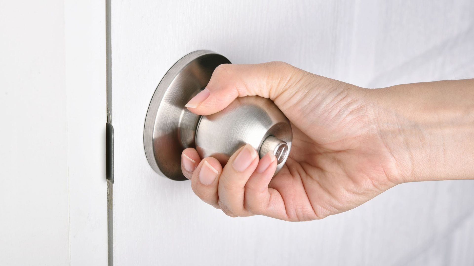 persons hand on a door handle twisting it open