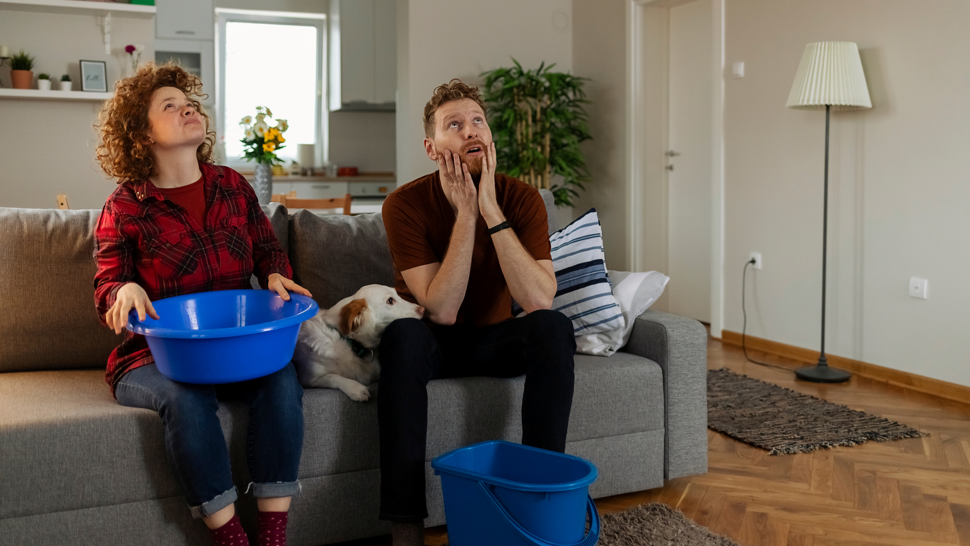 Two Florida tenants holding buckets to catch water from ceiling leak showing failure to maintain