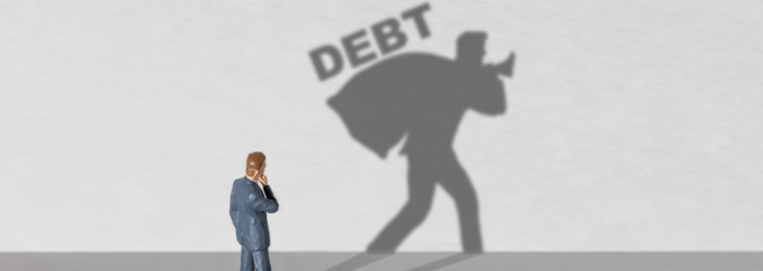 man looking at his shadow, he's carrying a bag that says debt on it