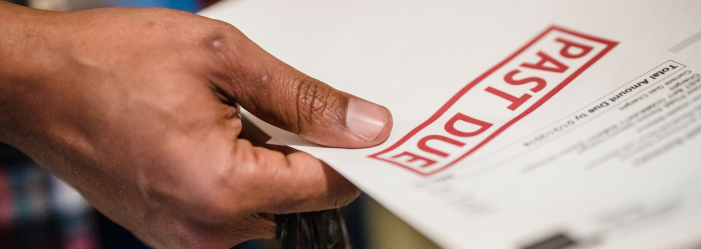 hand holding a paper that has a 'past due' stamp on it, representing the collections agency