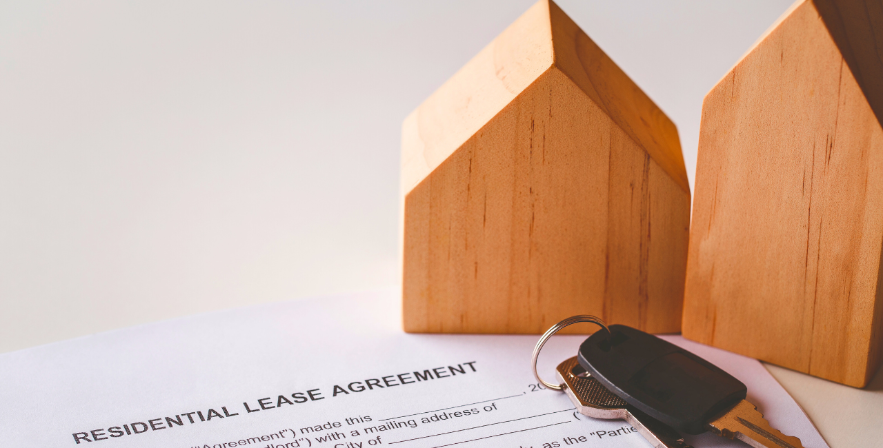 paper that says RESIDENTIAL LEASE AGREEMENT with keys and two wooden houses