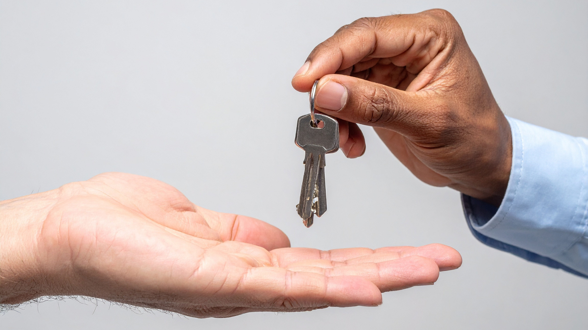 person's hand holding keys over another person's hand