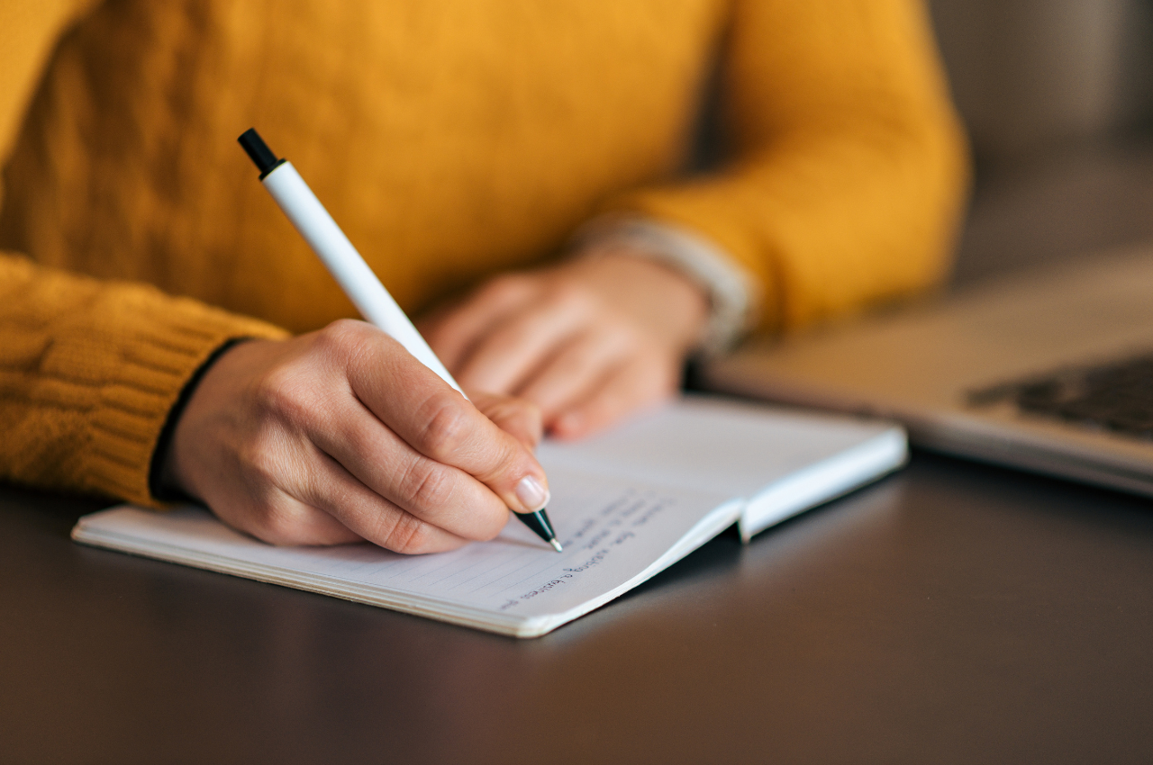 person in yellow sweater writing a letter