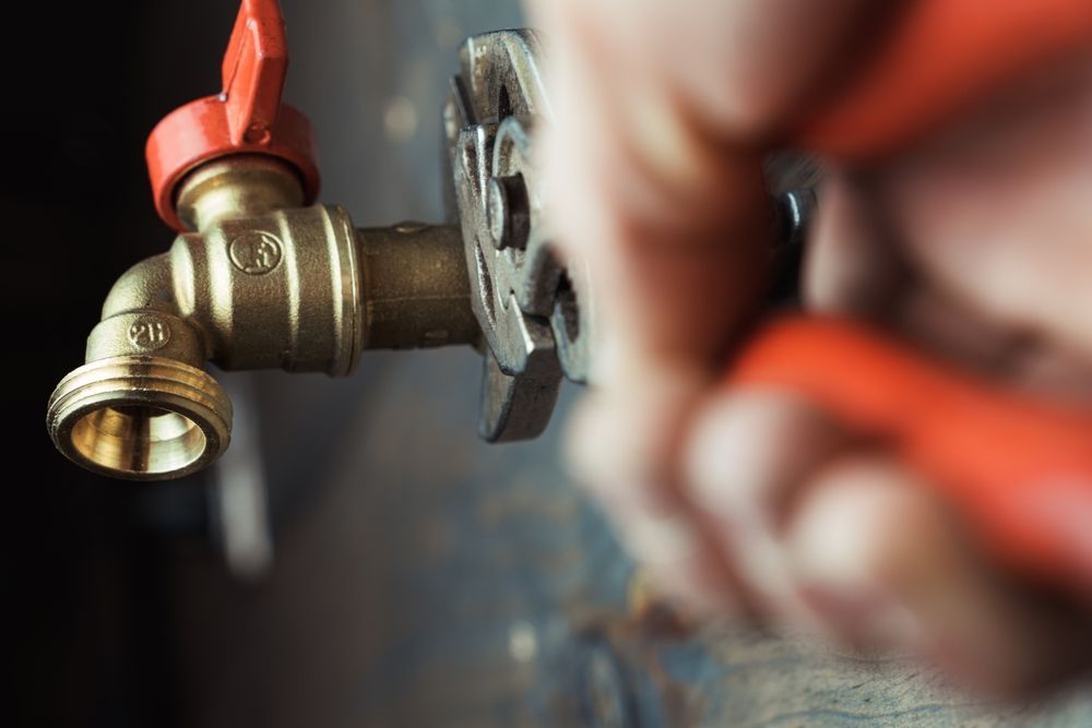 A Person is Fixing a Faucet With a Wrench — Otto’s Plumbing & Gasfitting in McDowall, QLD