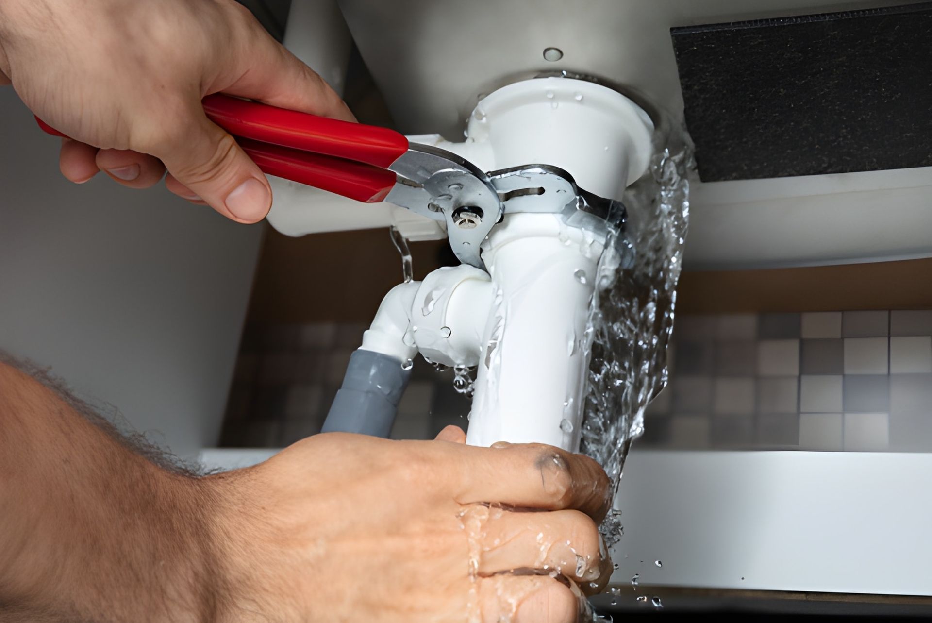 Plumber Tightening a Pipe Under a Sink With a Wrench — Otto’s Plumbing & Gasfitting in Grange, QLD